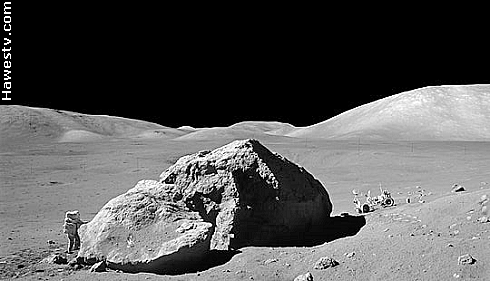 Art: 
       Apollo 16 astronaut standing beside house-size moon rock on the moon